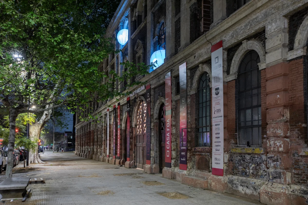 Fachada de ladrillo del Palacio Molina de noche, con esferas celestes asomando por ventanas en arco.